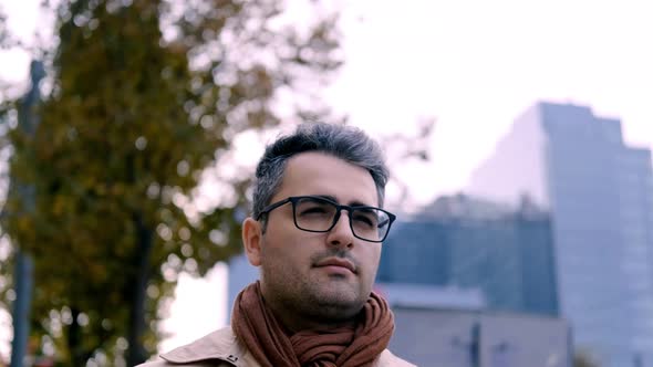 A Male Teacher Walks Around the City in a Beige Coat and Scarf