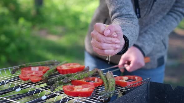 Making Grilled Vegetables  Adding Lomon Juice to Asparagus and Red Pepper on a Charcoal Grill