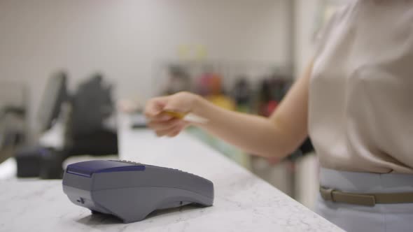 Unrecognizable Woman Paying with Card at Clothes Shop