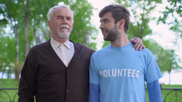 Aged Man and Male Volunteer Looking at Camera, Old People Assistance, Charity