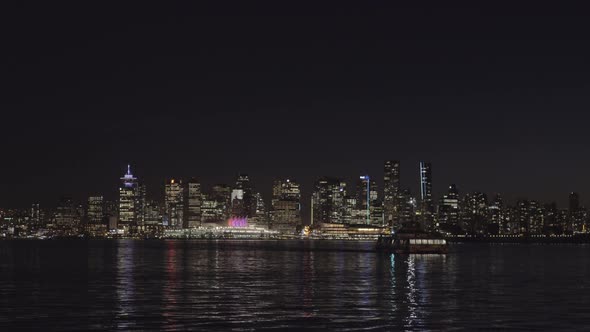 Sea bus approaching Lonsdale Quay, Vancouver skyline at night in background