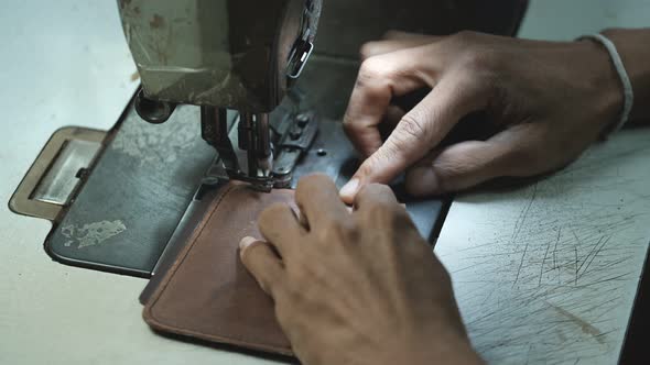 Close-Up Of Tailor Working On Sewing Machine in leather factory background