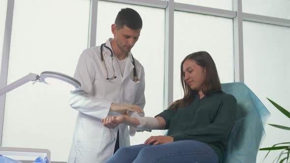 A Physical Therapist Applies a Bandage to a Patient'S Injured Arm
