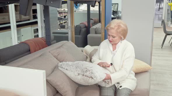 Happy Senior Woman Choosing Cushions for Her Living Room at Furniture Store