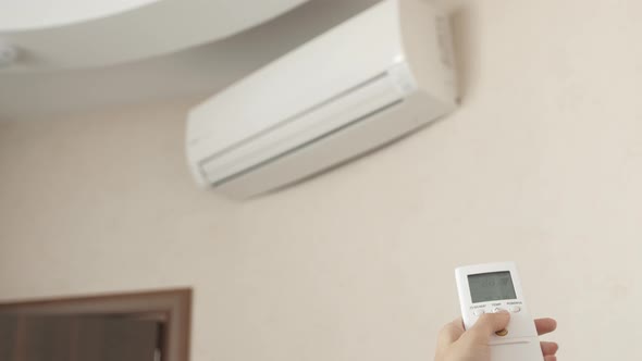 Woman Using Aircondition with Remote Control