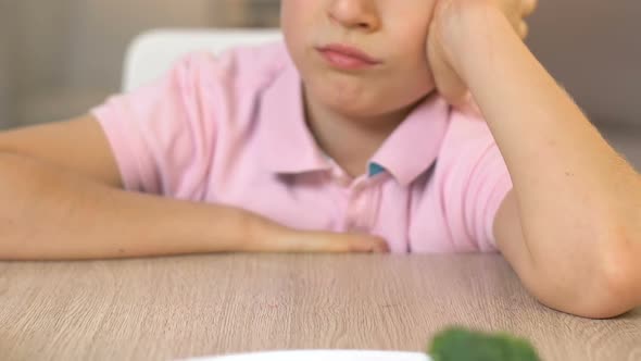 Upset Boy Looking at Broccoli With Disgust, Refusal to Eat, Vegetarian Lifestyle