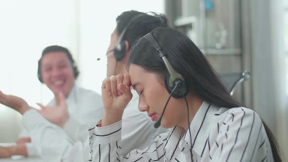 A Woman Of Three Asian Call Centre Agents Headache Because Two Colleagues Talking With Each Other