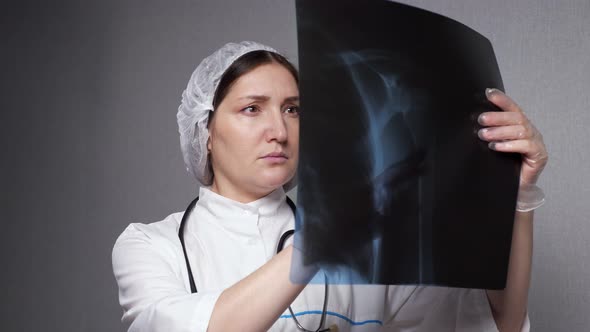 Lady Orthopedist Looks at Xray Picture in Clinic Office
