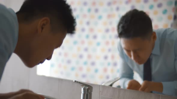 Close Up of Asian Businessman Washing Face in Bathroom