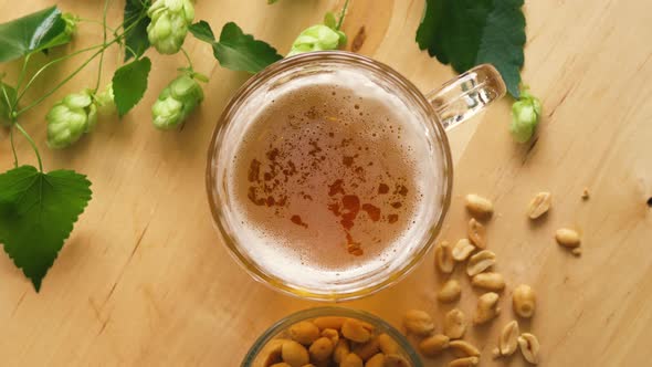 Top View of Beer with Foam and Salty Peanuts and on Wooden Table