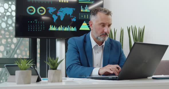 Businessman in Formal Clothes Sitting in front of Computer and Working Over Business Project 