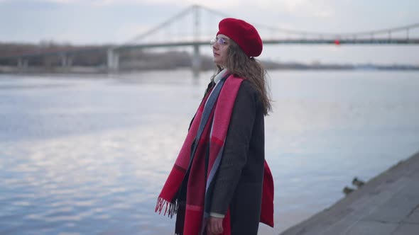 Side View of Young Slim Confident Woman Walking on Urban Embankment Admiring River