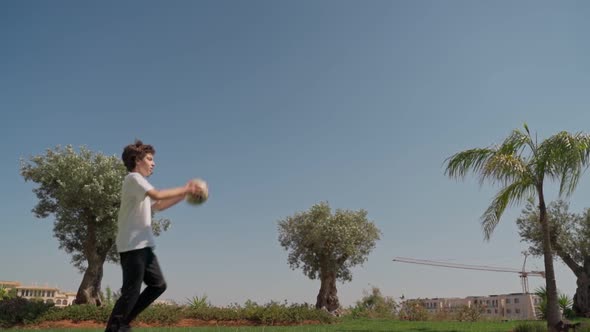 A Young Guy in Training Throws a Soccer Ball with Both Hands at an Out on a Grassy Court