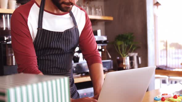 Focused owner using laptop at counter