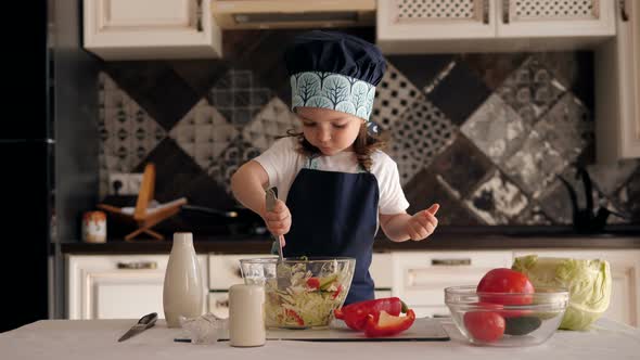 Little Girl Plays in Kitchen As a Cook, She Mixes Chopped Vegetables in a Plate