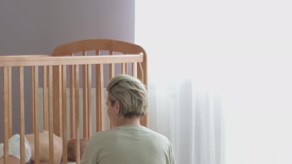 Mother Trying Calm Screaming Crying Baby Toddler Infant in Crib Put to Bed Cot