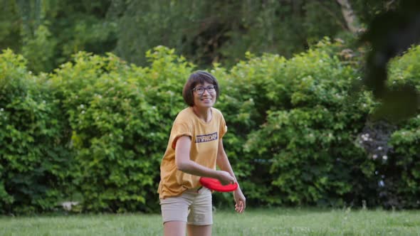 Mother and Son Play Frisbee on Grass Lawn