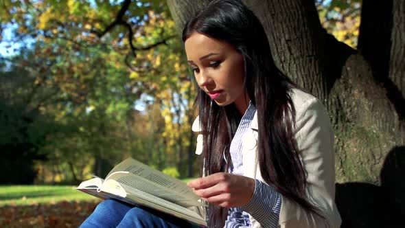 Slowmotion Young Beautiful Happy Woman Sits in Park and Reads a Book