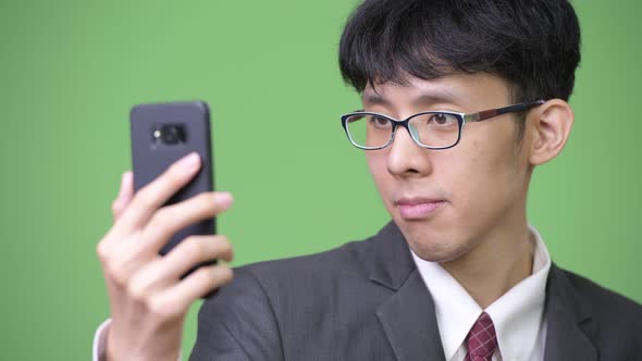 Young Asian Businessman Using Phone and Touching Screen