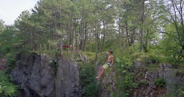 A man swinging while slacklining on a tightrope in the mountains