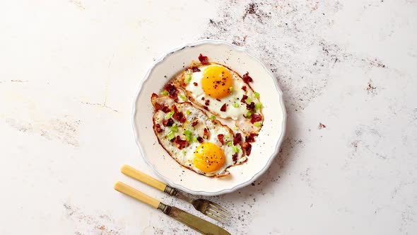 Two Fresh Fried Eggs with Crunchy Crisp Bacon and Chive Served on Rustic Plate