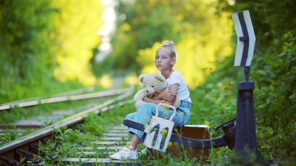 Sad Girl with Teddy Bear Sitting Near Railway Switches