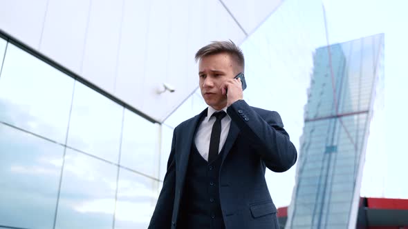 Trendy Businessman in Suit and Tie Use Smartphone Going Near Modern Building Exterior Steadicam