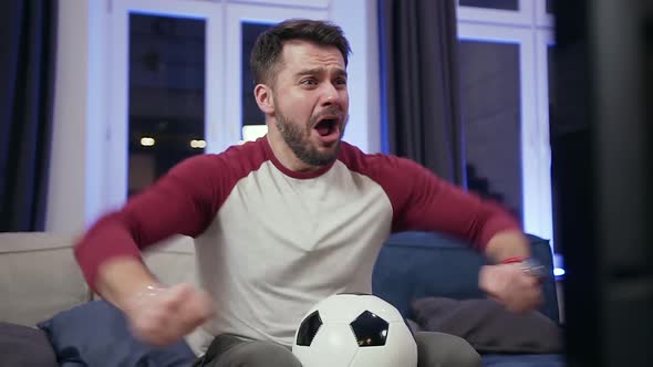 Guy Holding Ball in His Hands and Shouting "Goal" During Watching Football Match