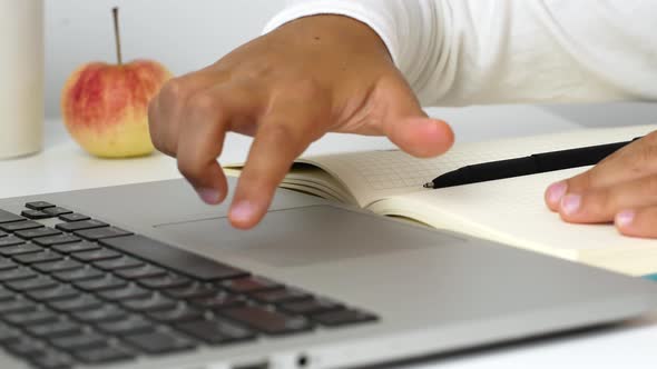 A child girl on distance learning sits in front of a laptop and does homework. Distance learning