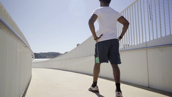 Rear View of Sporty African American Man Running on Bridge