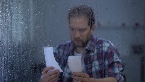 Sad Middle-Aged Man Putting Together Two Parts of Torn Photo