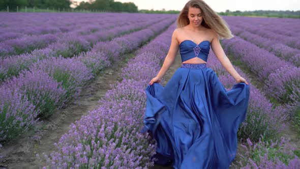 A Beautiful Young Woman in a Dress Enjoying a Stroll Through the Blooming Lavender Fields in