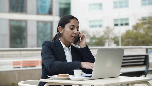 Businesswoman Using Laptop and Smartphone in Cafe