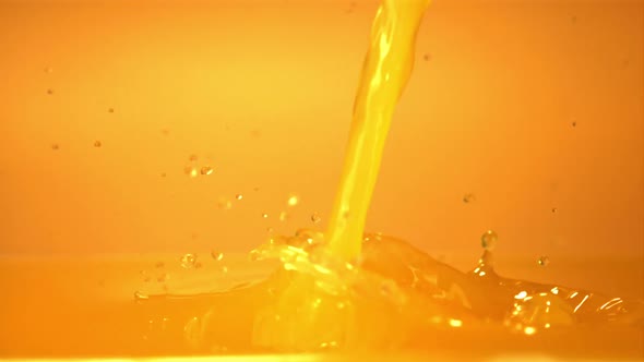 Super Slow Motion of the Stream of Orange Juice Pours with Splashes