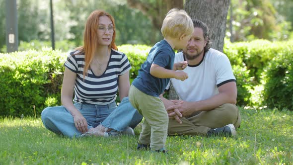 Family Spends Time in the Park  Sitting on the Grass