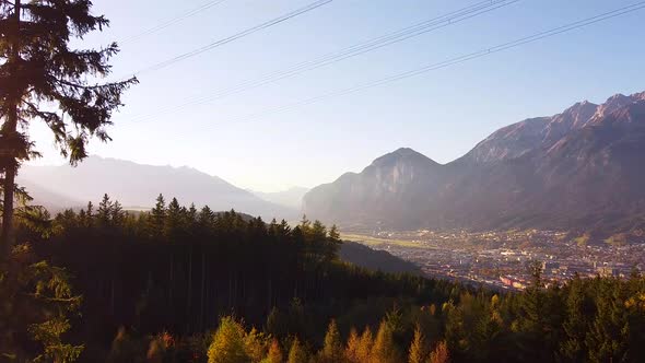 Areal drone overview of the city of Innsbruck, mountains in the background at sunset