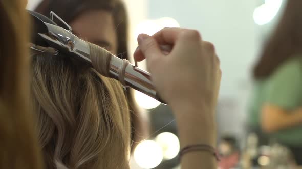 Closeup View of Stylist Hairdresser Making Hairstyle Using Curling Tongs