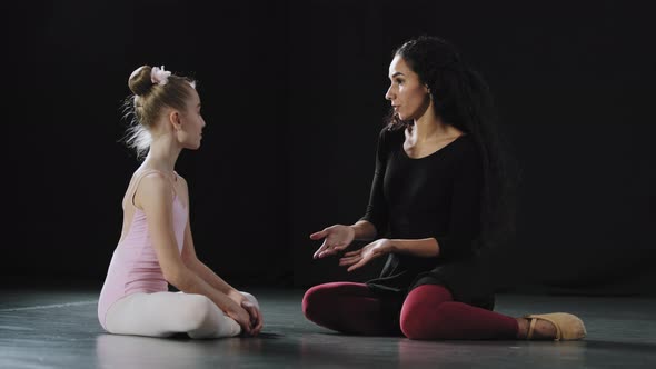 Little Girl Ballerina Dancer Beginner Acrobat Child in Leotard Sits on Floor in Dance Class with