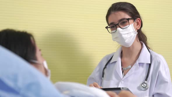 Doctor Wearing Face Mask Proficiently Talks with Patient at Hospital Ward