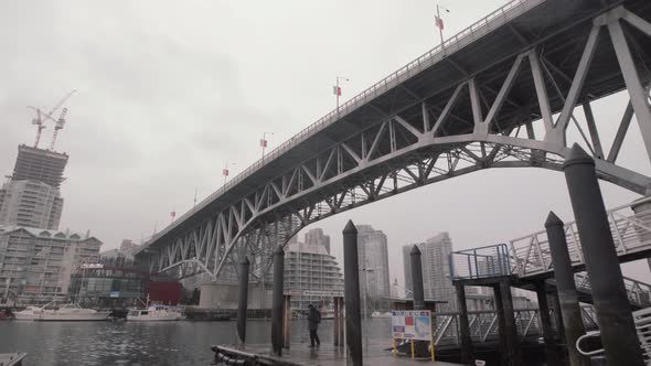 Man waiting for ferry under the Granville Island bridge on cloudy day