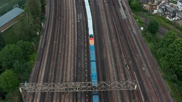 Pan up drone shot from expansive railway train tracks to London Skyline