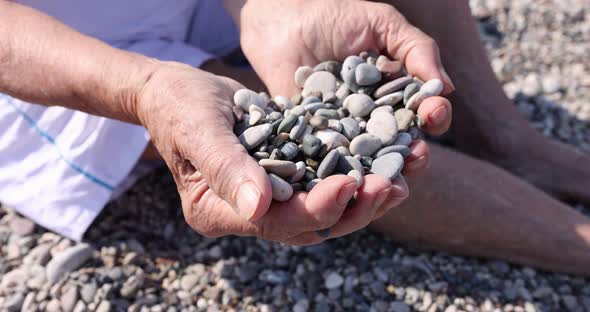 Elderly Woman Scattering Stones on Pebble Beach Closeup  Movie Slow Motion