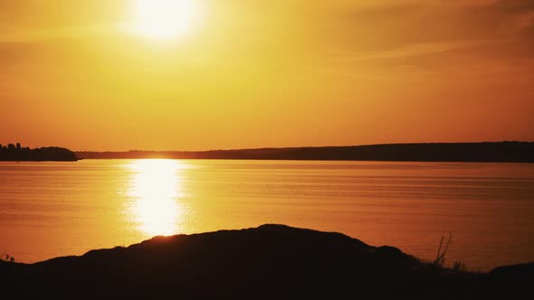 Amazing view of a golden sunset path over water surface and a biker. Silhouette of a male biker