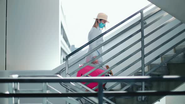 Slow Motion of Traveler in Blue Face Mask Walking Up By Empty Stairs in Airport