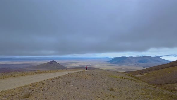 A Woman with a Backpack Walks in the Mountains