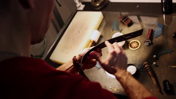 A Man Lubricates the Edge of a Leather Belt