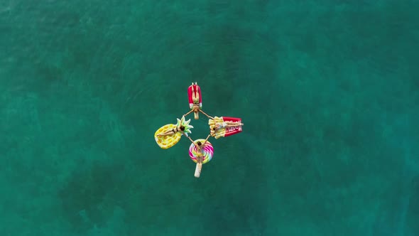 Aerial view group of women holding hands on inflatable mattress on Atokos.