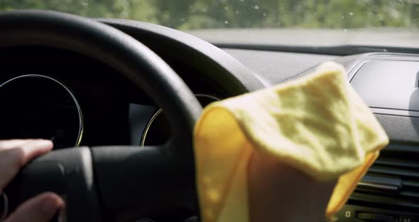 Car Cleaning Concept. The Man's Hand Cleans Panel in the Car From the Dust Using a Yellow Cloth.