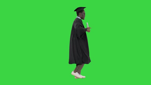 Excited African American Male Student in Graduation Robe Dancing with His Diploma While Walking on a