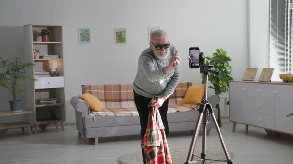 Modern Hobby of Pensioner Grandfather Wearing Glasses Shows Trick with Disappearing on Mobile Phone